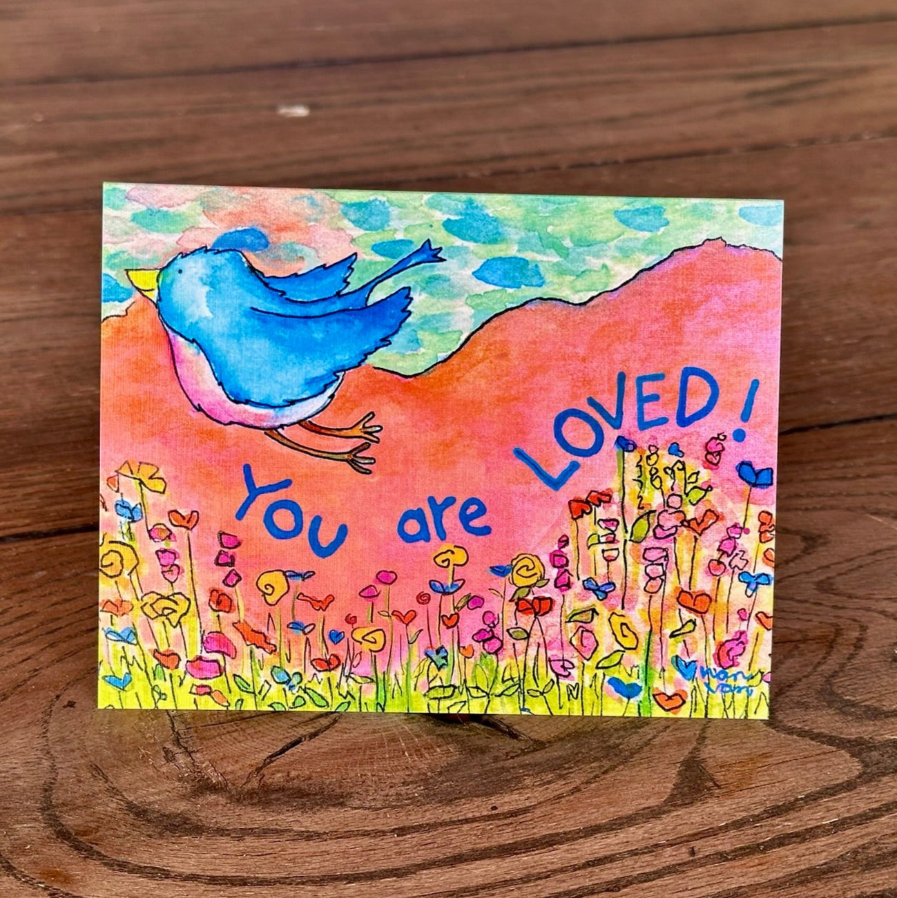 You are loved text with bluebird flying over flowers mountain background greeting card